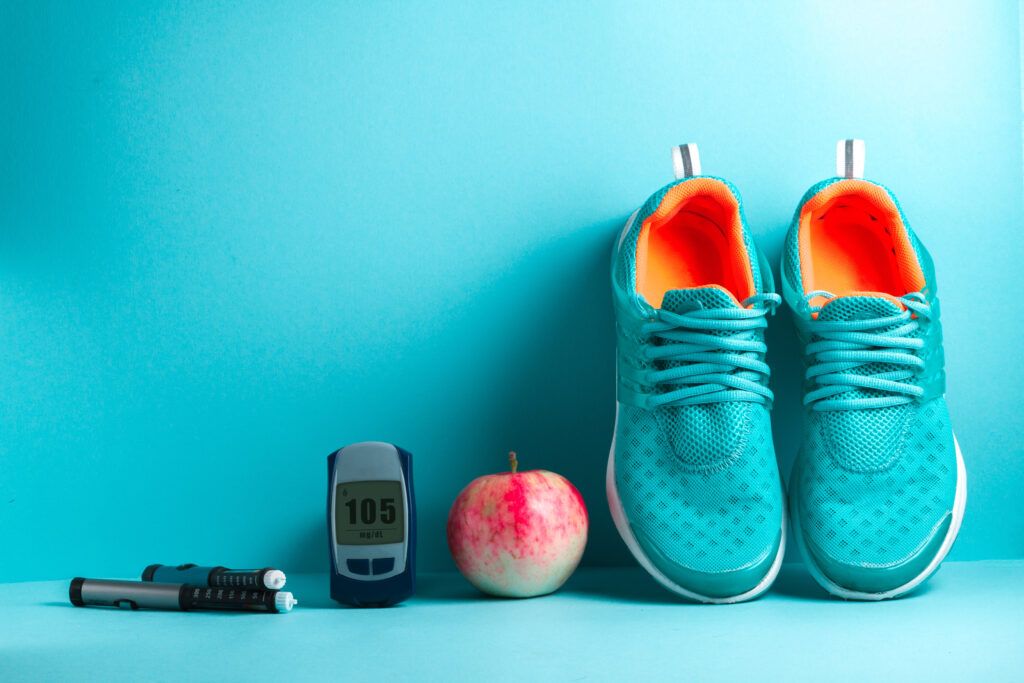 Running shoes, an apple, and a glucose monitor displaying 105 mg/dl glucose